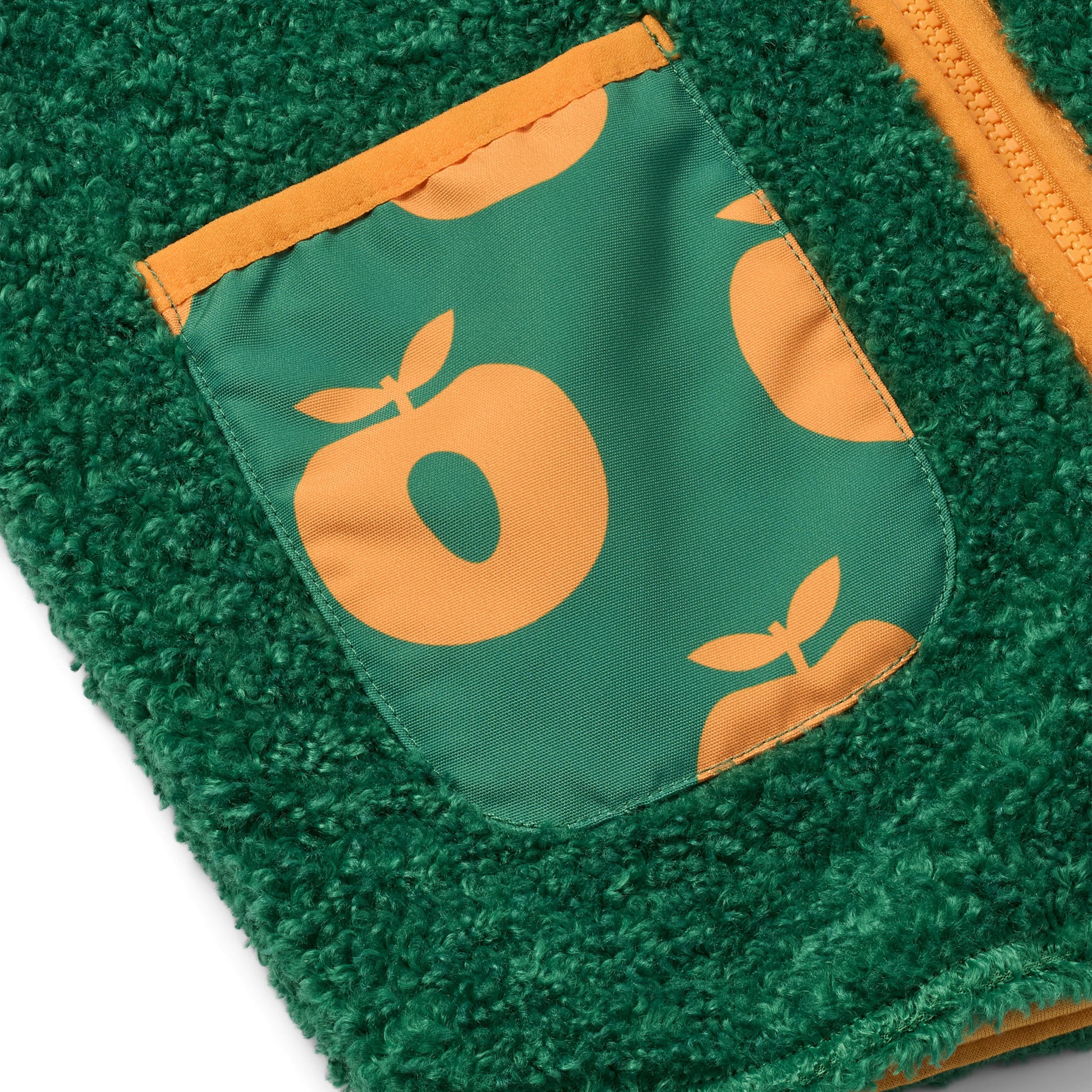 Grøn vest med orange æbler nærbillede af lommen