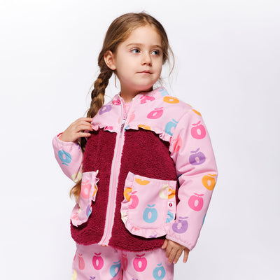 Pige med en lyserød jakke med forskelligfarvede æbler